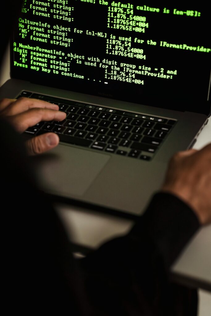 Current image: Crop anonymous male cyber spy hacking portable computer with codes on screen while sitting at table